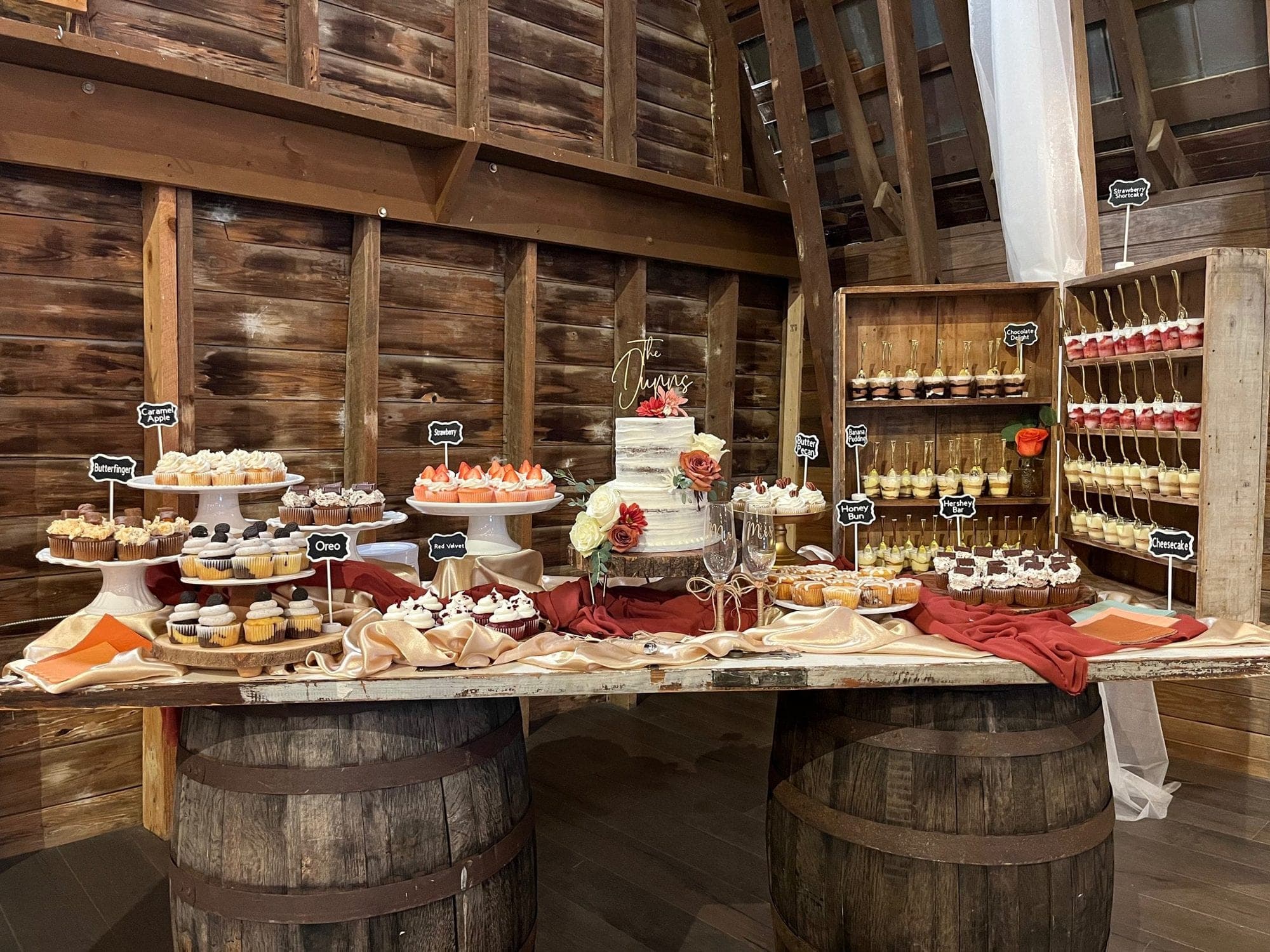 Rustic dessert bar styled on whiskey barrels with a stocked cupcake display