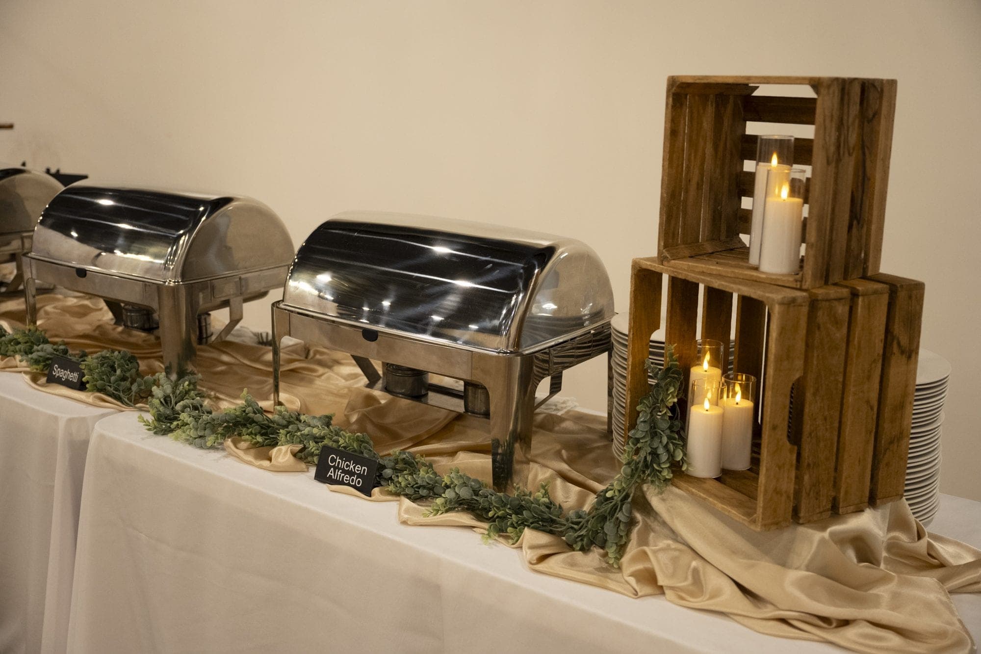 Chafing dishes dressed with garland, candles, and wooden crates on a full buffet line
