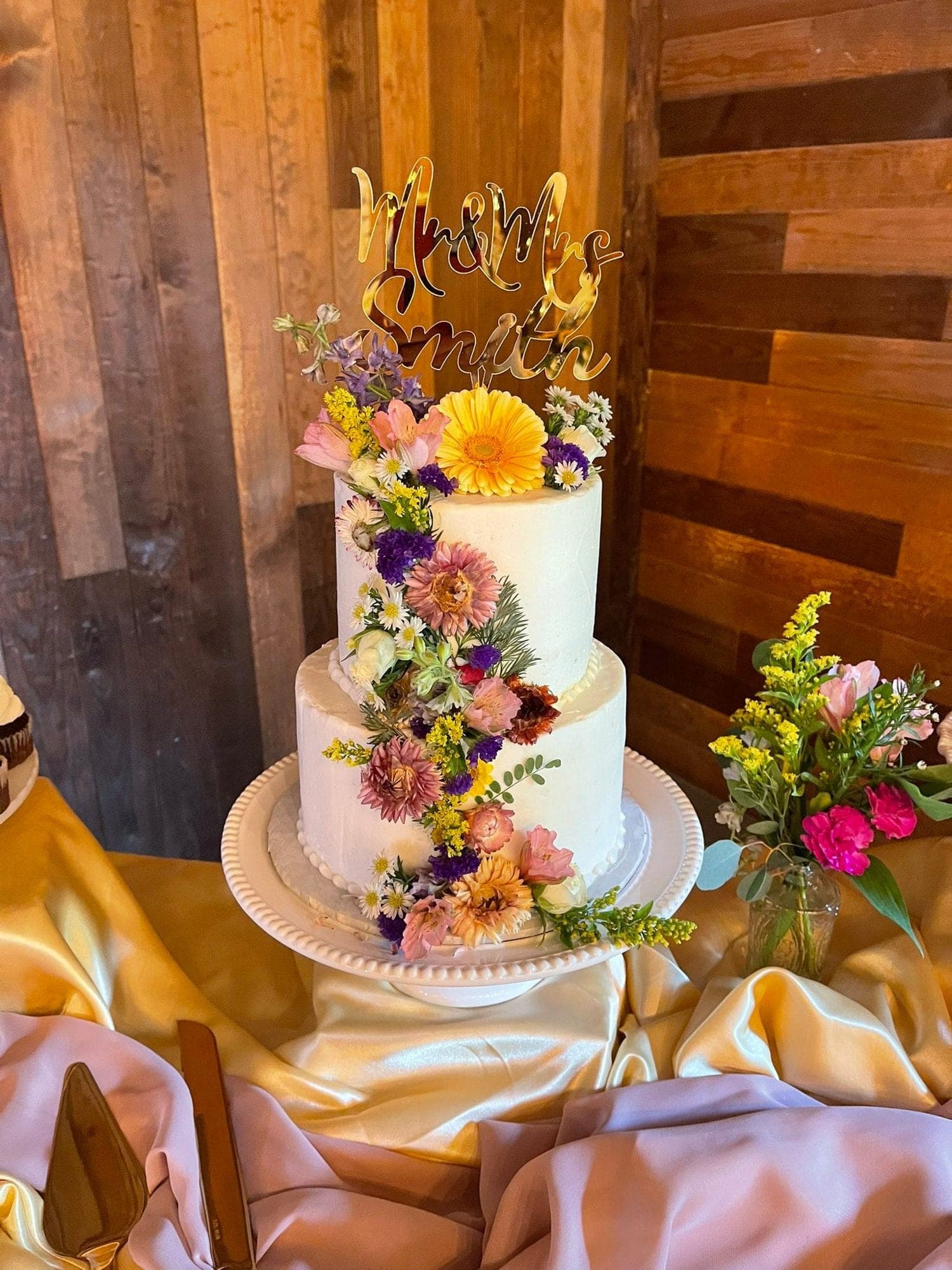 A buttercream wedding cake crowned with fresh wildflowers